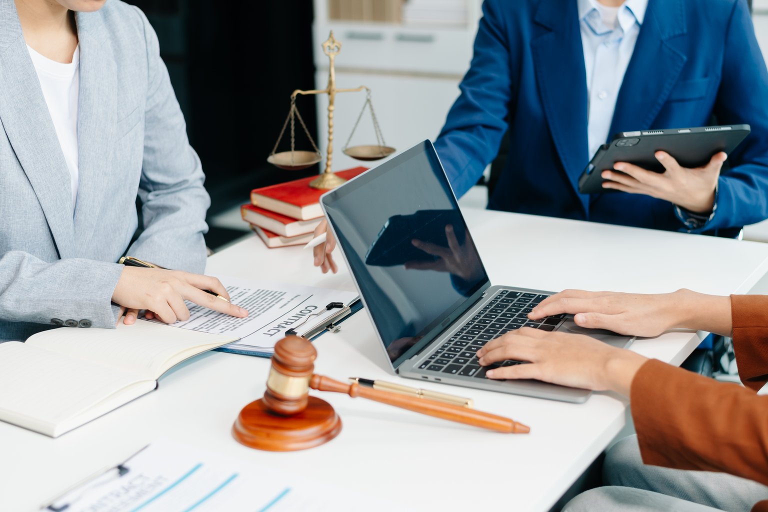 Business associates reviewing a contract at a desk with a gavel and laptop