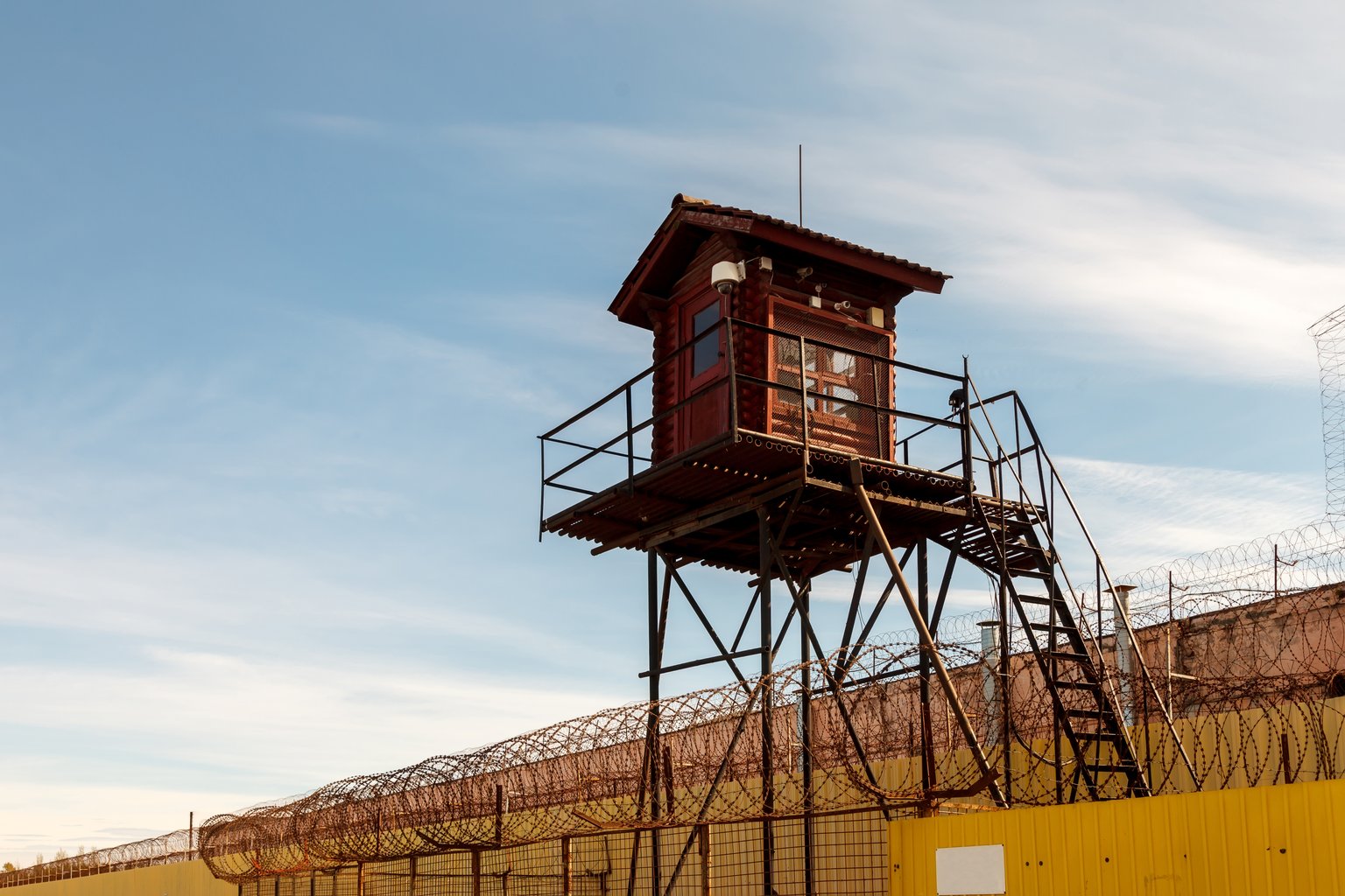 Correctional facility watchtower behind a razor-wire fence