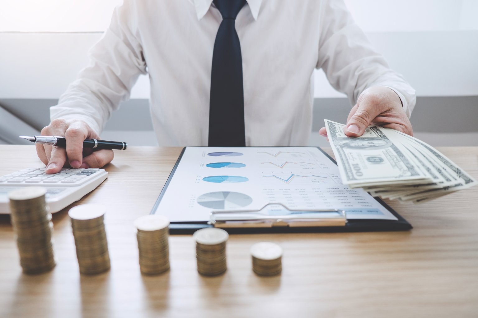 Staff reviewing collection reports with cash, coins and a calculator